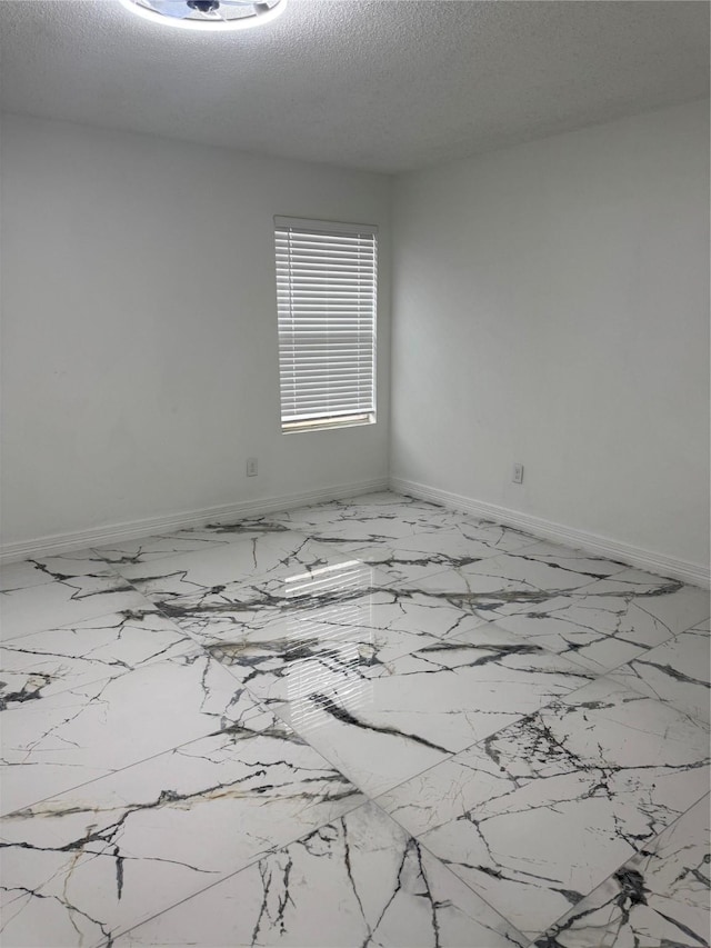 spare room featuring baseboards and a textured ceiling