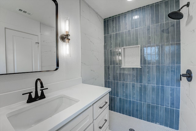 full bath with vanity, tile walls, visible vents, and tiled shower