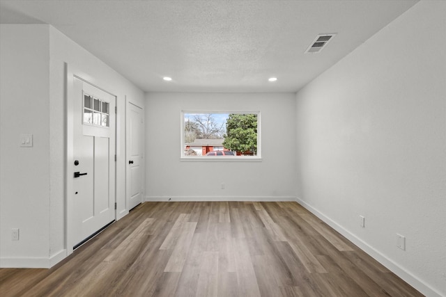 interior space with visible vents, baseboards, recessed lighting, wood finished floors, and a textured ceiling