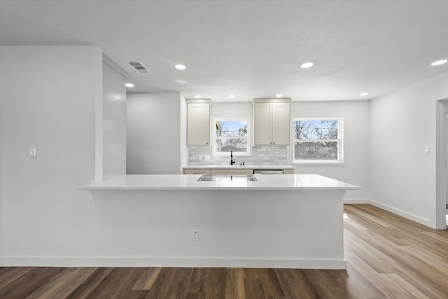 kitchen featuring visible vents, wood finished floors, light countertops, decorative backsplash, and baseboards