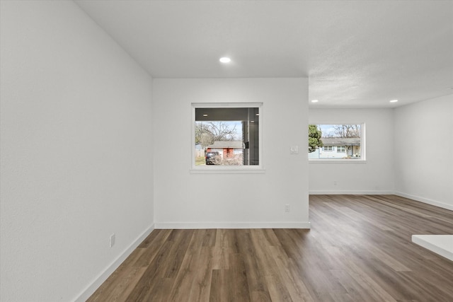 empty room with recessed lighting, wood finished floors, and baseboards