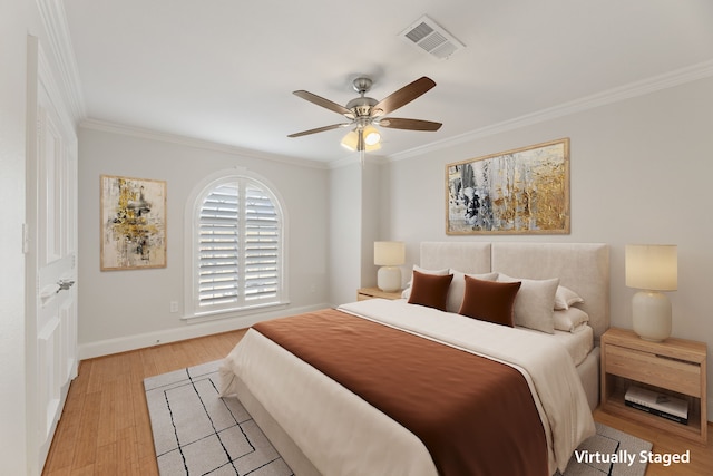 bedroom featuring ceiling fan, visible vents, baseboards, light wood finished floors, and crown molding