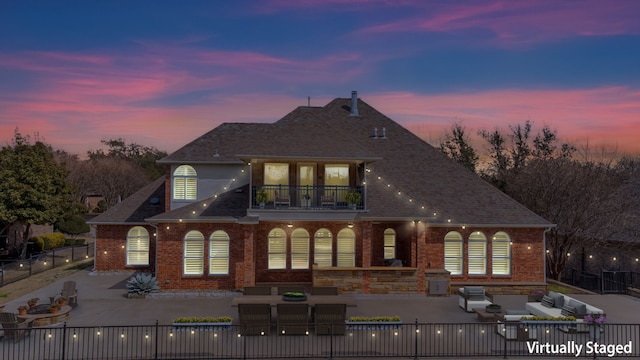 rear view of house with brick siding, a patio, a balcony, a fenced backyard, and an outdoor living space