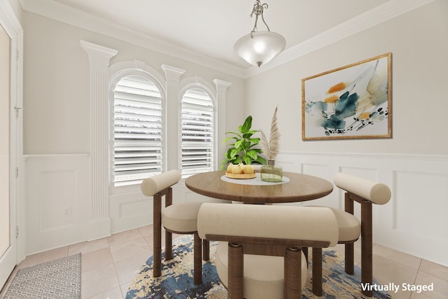 dining room with wainscoting, ornamental molding, light tile patterned flooring, and a decorative wall