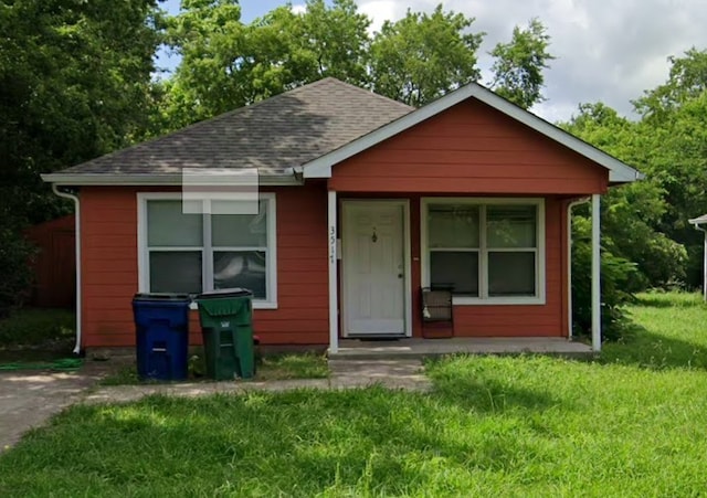 bungalow featuring a shingled roof and a front lawn