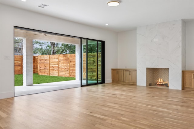 unfurnished living room featuring baseboards, visible vents, light wood-type flooring, a fireplace, and recessed lighting