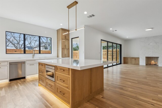 kitchen with stainless steel appliances, a fireplace, visible vents, light countertops, and light wood-type flooring