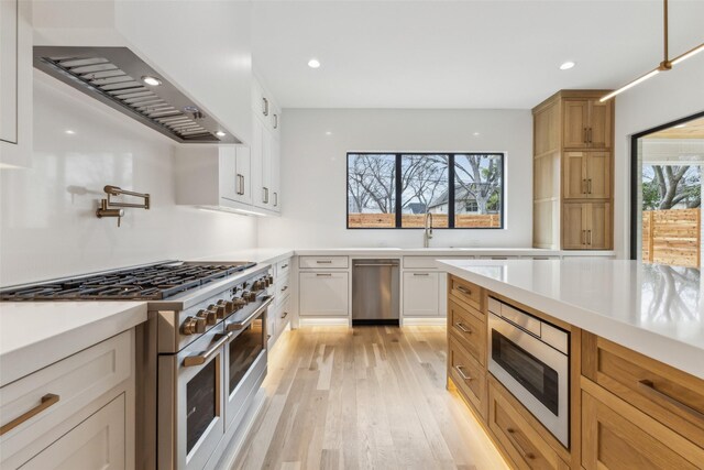 kitchen featuring appliances with stainless steel finishes, a wealth of natural light, light countertops, and a sink