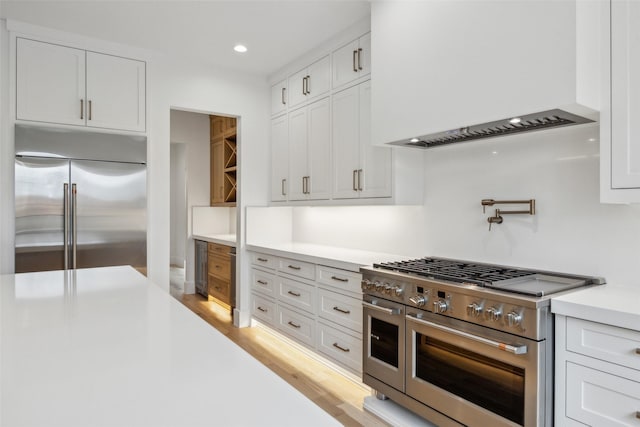 kitchen featuring premium range hood, high quality appliances, white cabinets, and light countertops