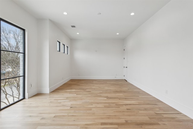 unfurnished room with baseboards, light wood-type flooring, visible vents, and recessed lighting