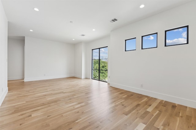 empty room featuring light wood-type flooring, visible vents, baseboards, and recessed lighting