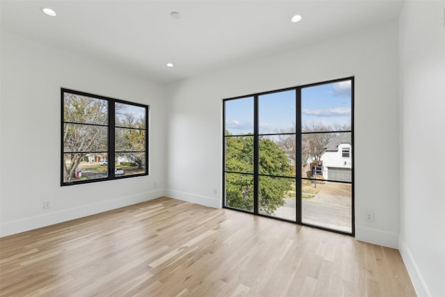 empty room featuring baseboards, plenty of natural light, and light wood finished floors