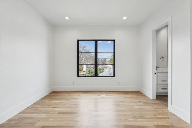 empty room featuring recessed lighting, baseboards, and light wood finished floors