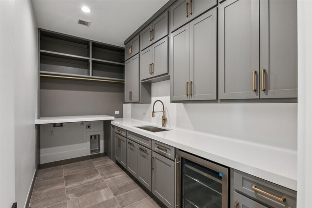 kitchen featuring gray cabinetry, beverage cooler, a sink, light countertops, and open shelves