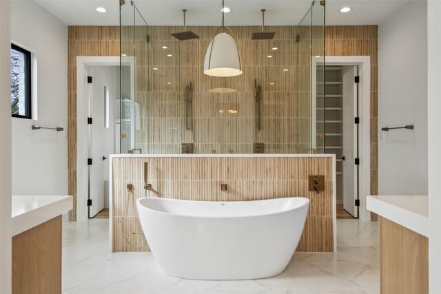 full bathroom featuring a soaking tub, marble finish floor, tile walls, and a stall shower