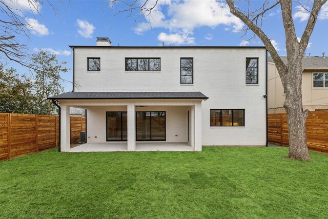 rear view of house featuring brick siding, a patio, a fenced backyard, and a lawn