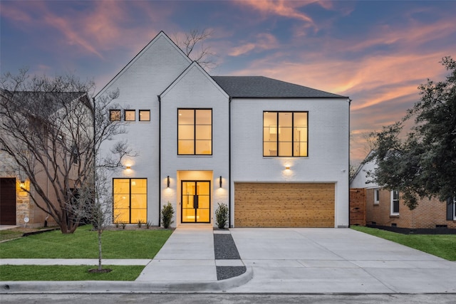 view of front of house featuring a garage, a front yard, concrete driveway, and brick siding