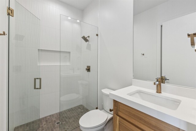 full bathroom featuring a shower stall, toilet, and vanity