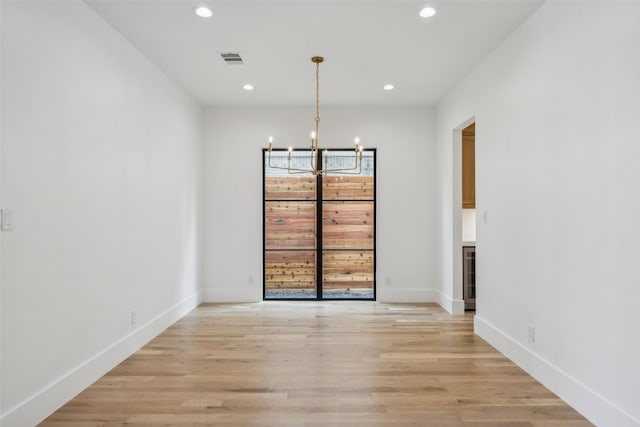 unfurnished dining area featuring baseboards, visible vents, an inviting chandelier, light wood-style floors, and recessed lighting