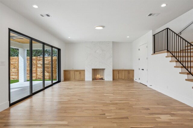 unfurnished living room with recessed lighting, visible vents, light wood finished floors, and a premium fireplace