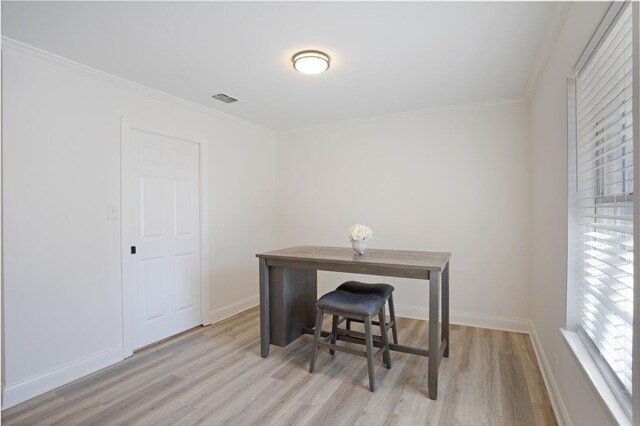 office area featuring baseboards, light wood-type flooring, visible vents, and crown molding