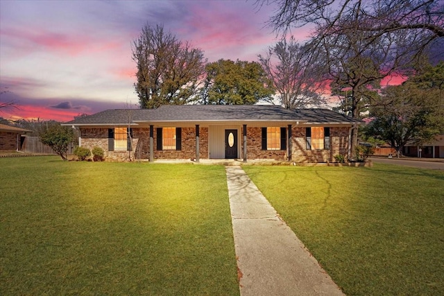 single story home with brick siding and a yard