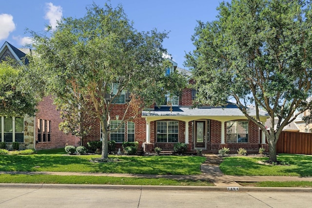 view of front facade featuring brick siding, a porch, a front yard, and fence