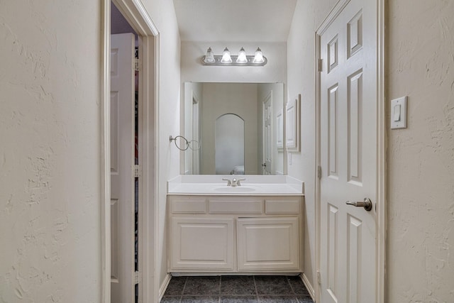 bathroom with tile patterned floors, vanity, and a textured wall