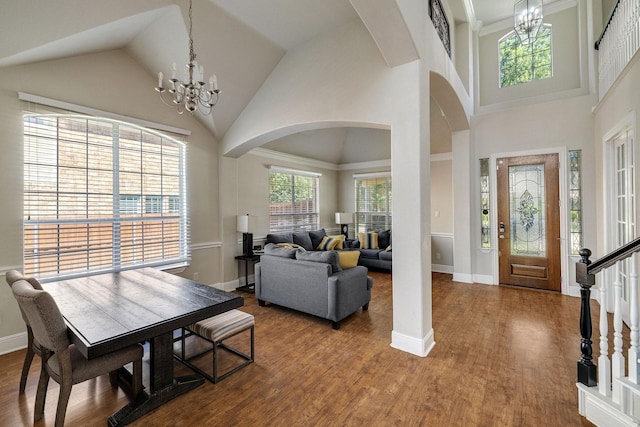 foyer entrance with a chandelier, arched walkways, and wood finished floors