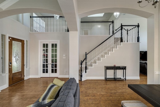 foyer entrance featuring french doors, stairway, a towering ceiling, and wood finished floors