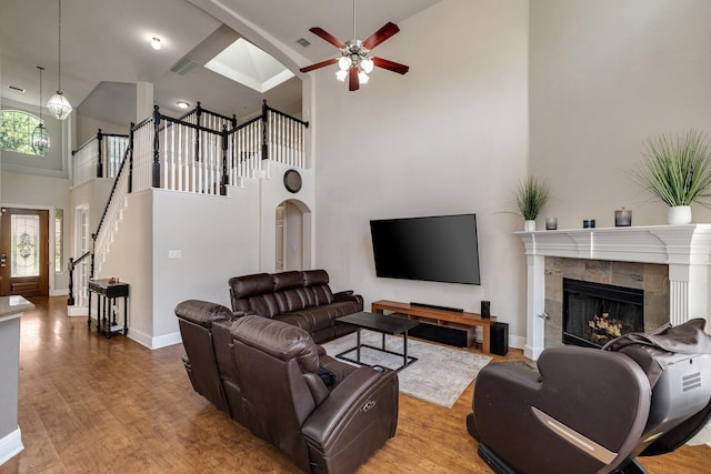 living room featuring visible vents, wood finished floors, a tile fireplace, baseboards, and stairs