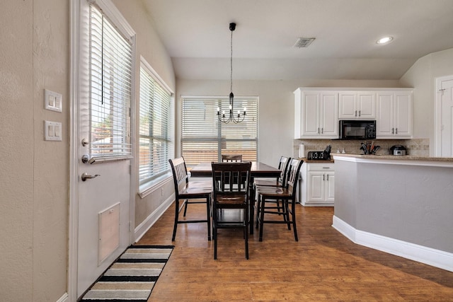 dining area with baseboards, visible vents, dark wood-style flooring, vaulted ceiling, and a notable chandelier