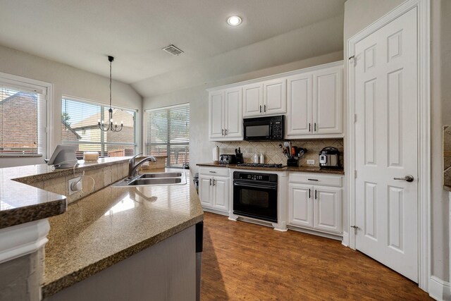 kitchen with visible vents, lofted ceiling, black appliances, white cabinetry, and a sink