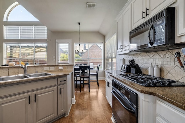 kitchen with visible vents, light wood-style flooring, a sink, black appliances, and backsplash