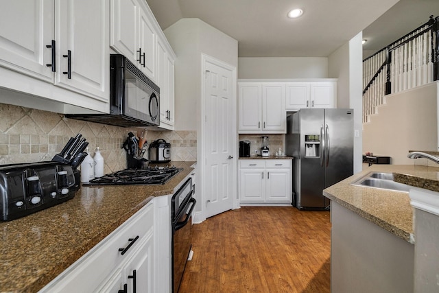 kitchen featuring tasteful backsplash, white cabinetry, a sink, wood finished floors, and black appliances