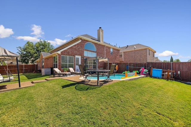 rear view of property featuring a fenced backyard, a lawn, a patio, and brick siding