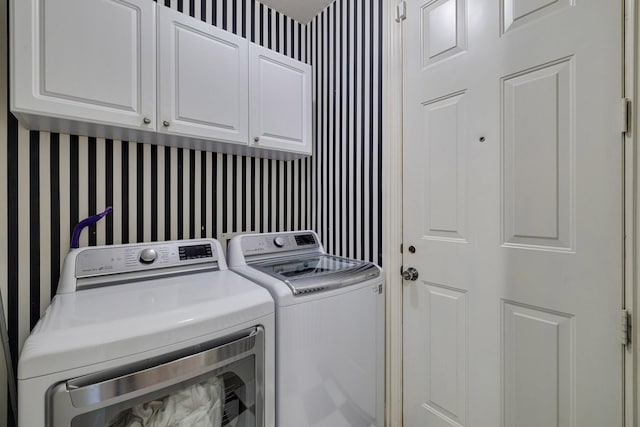 laundry room with wallpapered walls, washing machine and dryer, and cabinet space