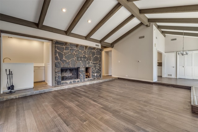 unfurnished living room with a notable chandelier, a fireplace, visible vents, and wood finished floors