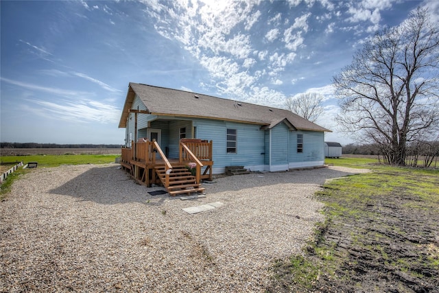 back of property with a shingled roof and a deck