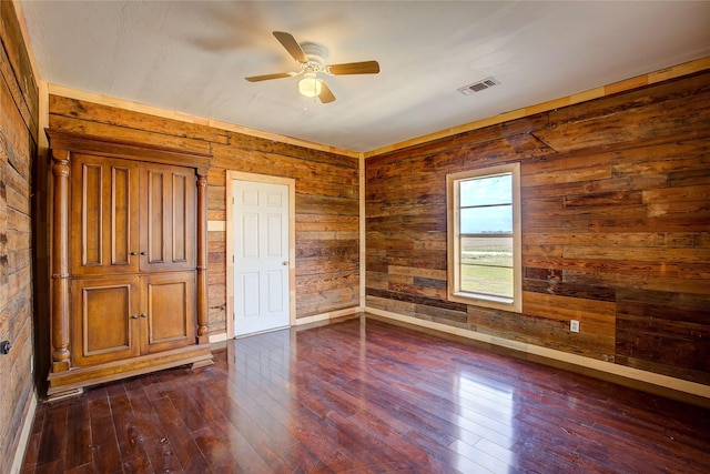 unfurnished bedroom featuring ceiling fan, dark wood-style flooring, visible vents, and baseboards