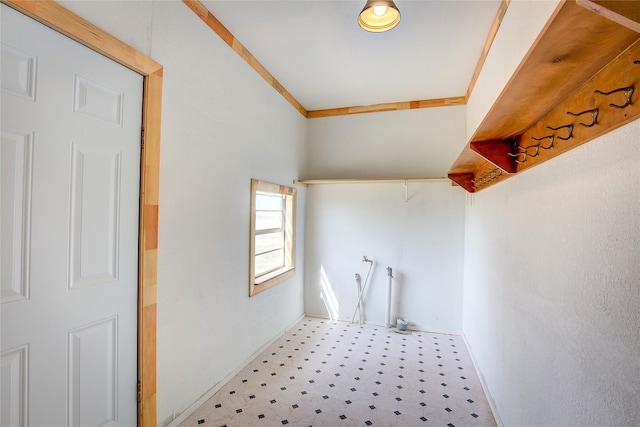 clothes washing area with light floors, ornamental molding, and baseboards