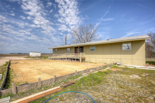 back of property with a deck, a storage shed, an outbuilding, and fence