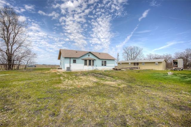 rear view of property with cooling unit and a yard