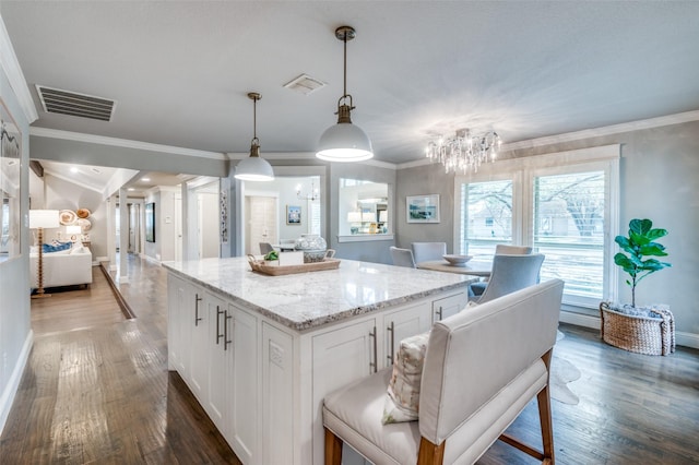 kitchen featuring white cabinetry, a kitchen island, visible vents, and wood finished floors