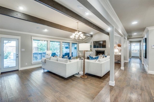 living room with a large fireplace, baseboards, ornamental molding, wood finished floors, and a chandelier