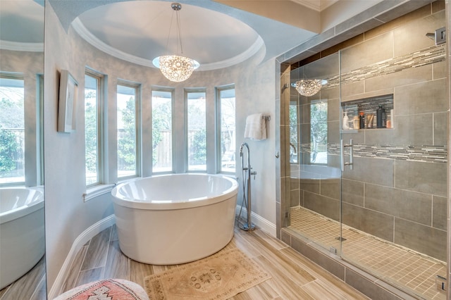 full bathroom featuring a chandelier, ornamental molding, a stall shower, and a freestanding tub