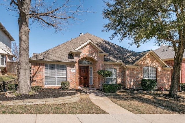 view of front of house featuring brick siding and roof with shingles