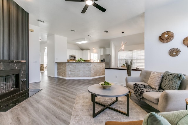 living room featuring lofted ceiling, visible vents, a premium fireplace, and wood finished floors