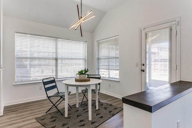 dining room featuring lofted ceiling, baseboards, and wood finished floors