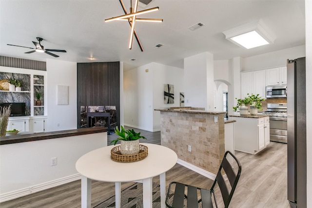 dining space featuring arched walkways, ceiling fan, light wood-type flooring, and visible vents